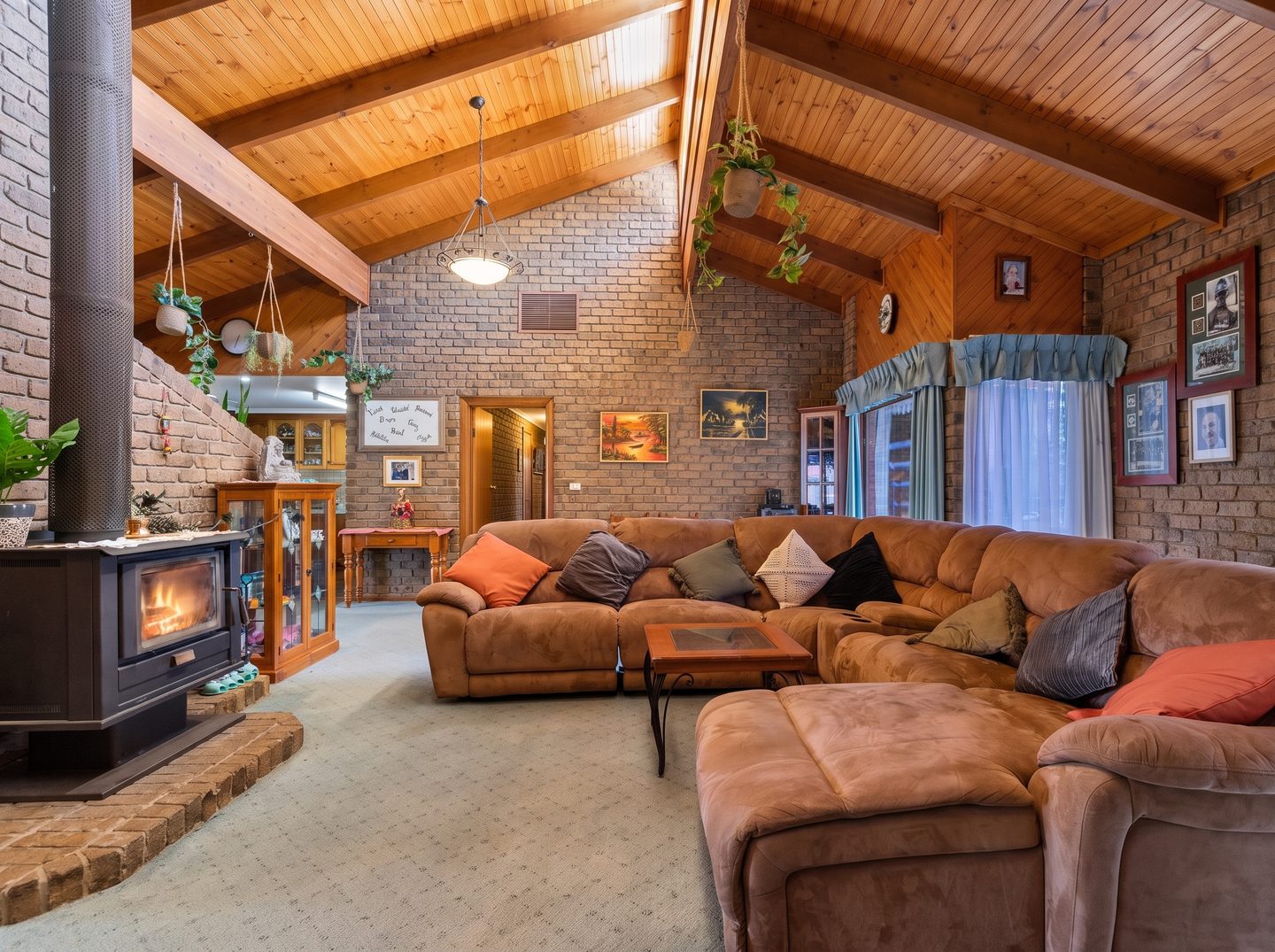 Family room with a pitched timber ceiling, exposed brick and combustion heater