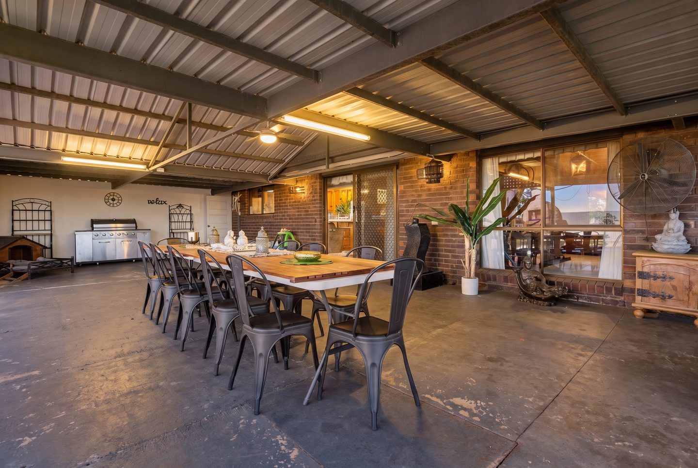 Large covered entertaining area beside the brick home