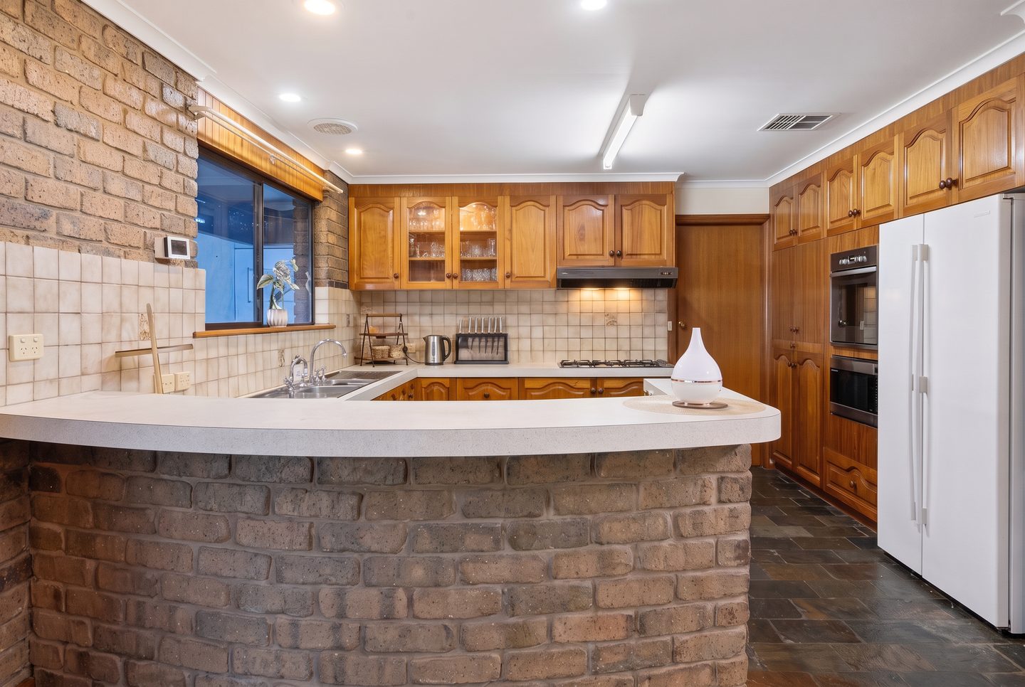 Timber kitchen cabinetry and curved brick breakfast bar